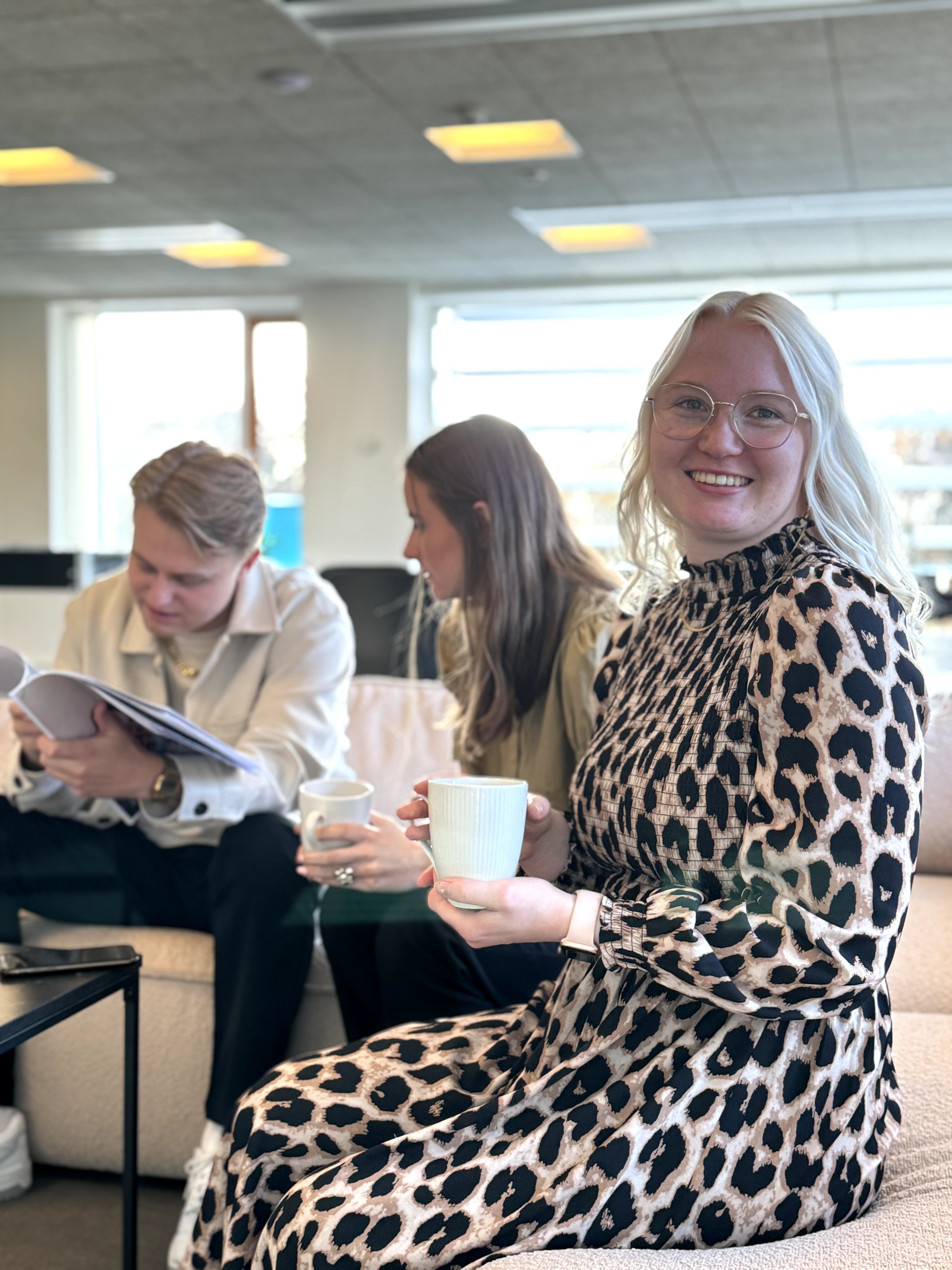 Ceciliea from pensopay, smiling with a coffee cup in hand at the office in Vejle.