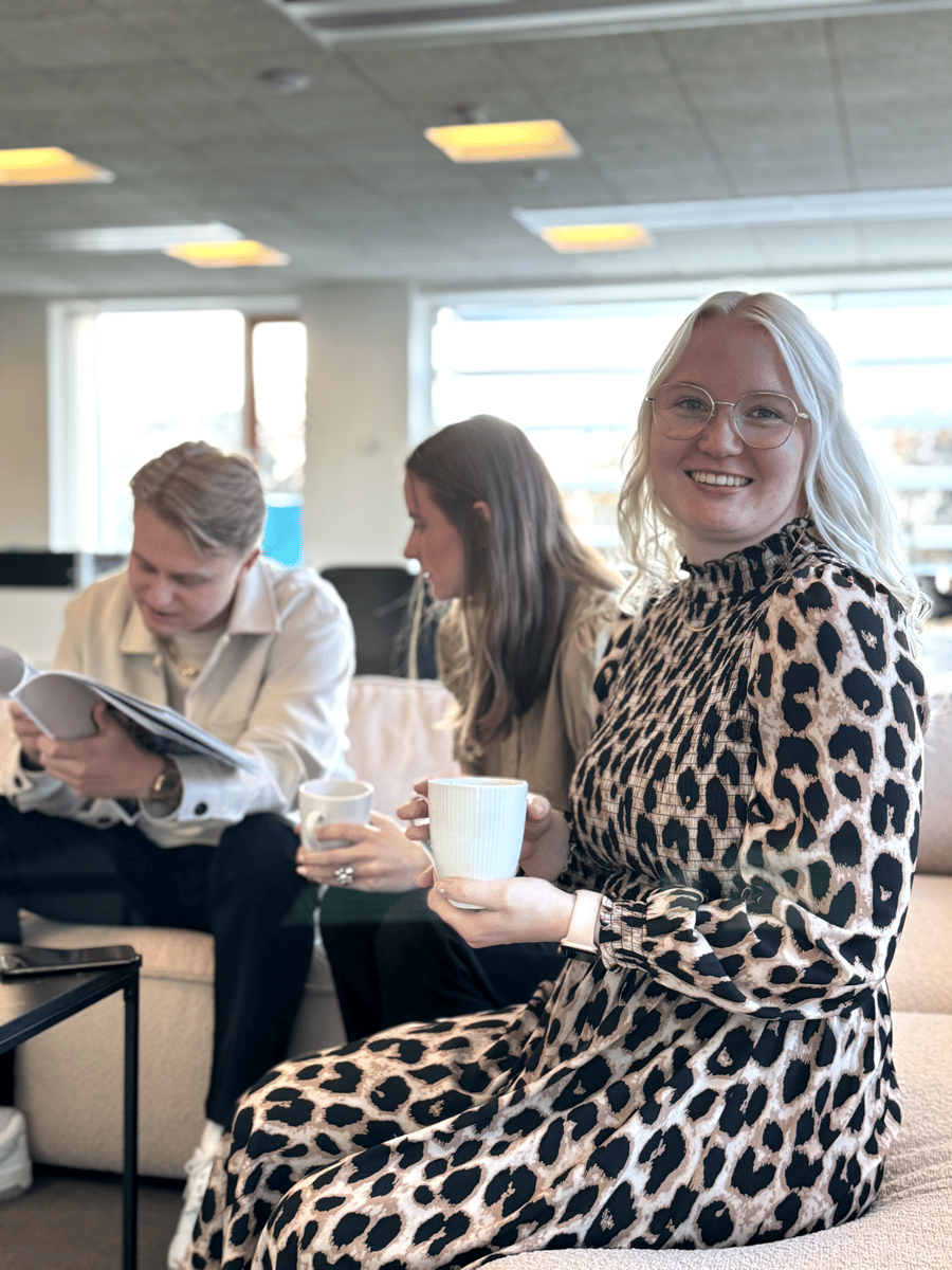 Ceciliea fra pensopay, der smiler med en kaffekop i hånden, på kontoret i Vejle.